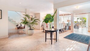 A spacious lobby with a marble floor, a round table with chairs, and large potted plants. - Tenis Villa 18 in Casa De Campo (La Romana)
