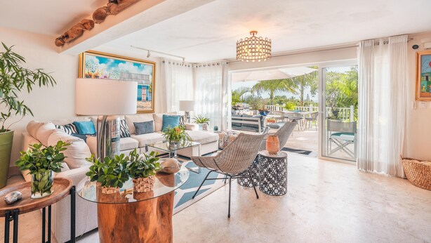 A spacious living area with a sofa, chairs, and a coffee table. There is a large window with curtains, a chandelier, and a painting on the wall. - Tenis Villa 18 in Casa De Campo (La Romana)