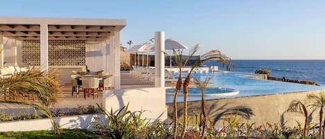 A resort with a pool, lounge chairs, and a view of the sea.
