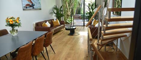 Un salon moderne comprenant un coin repas, un escalier et une grande fenêtre donnant sur l’extérieur.