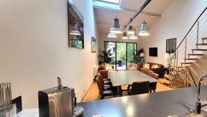 Et moderne køkken med en stor ø, rustfrie hvidevarer og en trappe, der fører op til en etage.
