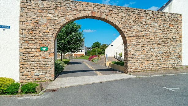 A stone archway leading to a street with a sign reading "A STERNE 11". - Le P'tit Loup de Mer - Appt proche plage, terrasse (Saint-Nic)