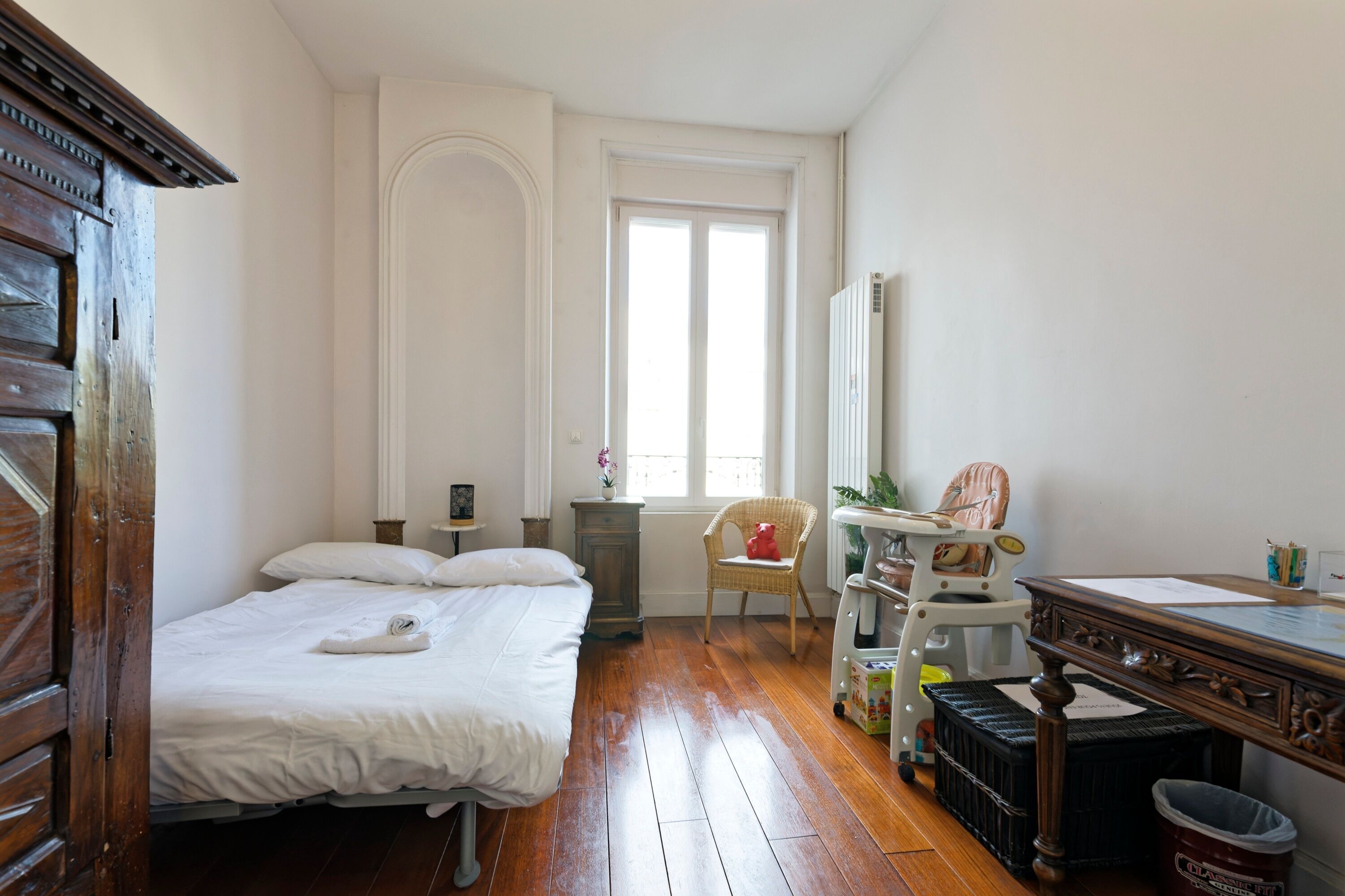 A bedroom with a wooden bed, a chair, a desk, and a window.