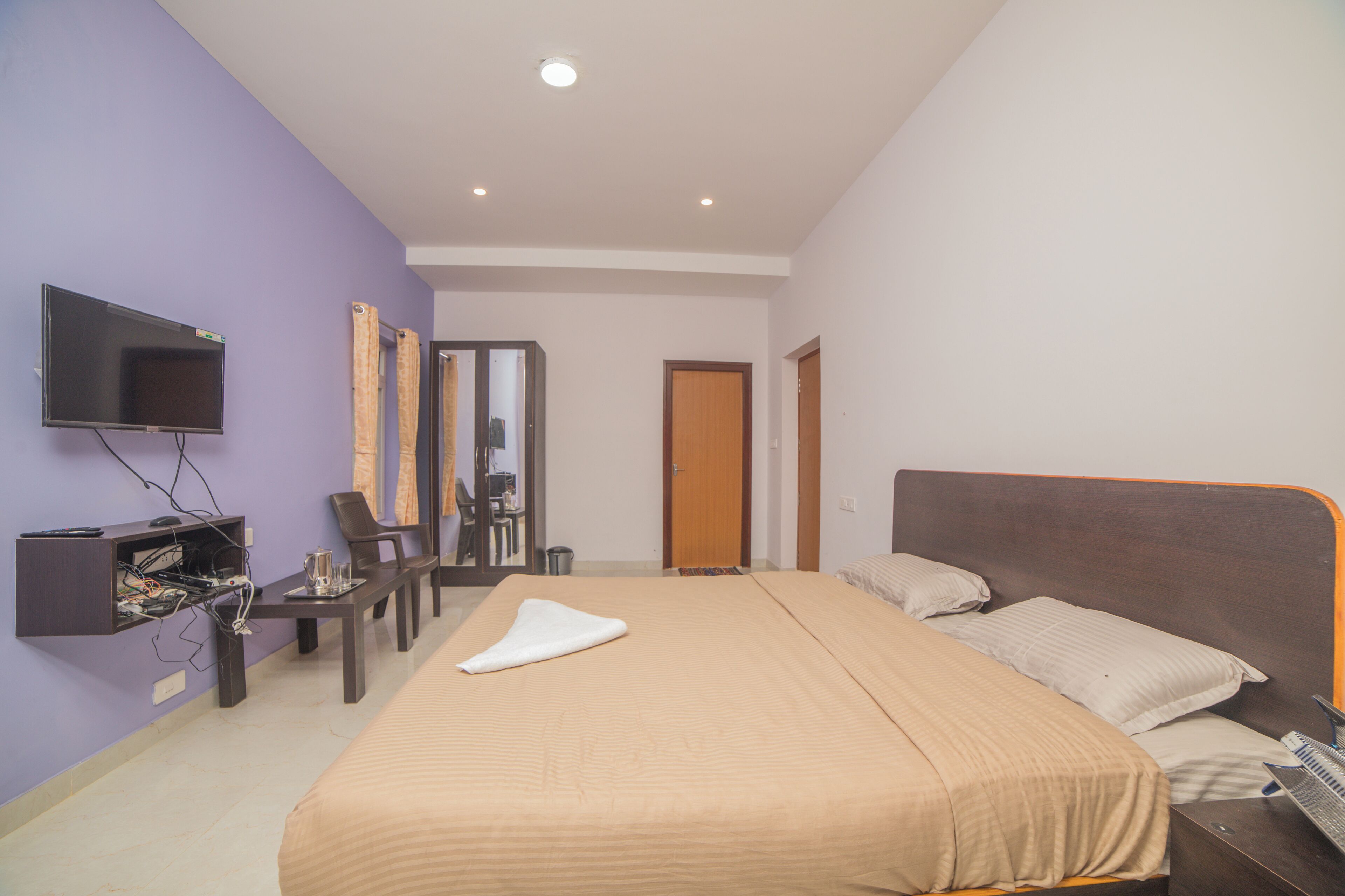 Una habitación de hotel con cama, televisión, escritorio y espejo.