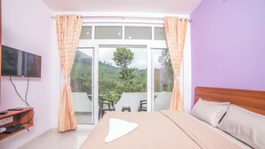 Un dormitorio con una cama grande, un televisor en la pared y un balcón con sillas.