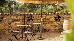 Een terras met rieten parasols, stenen muren en rustieke meubels.