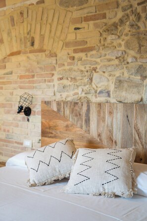 Una cama con dos almohadas y un cabecero de madera frente a una pared de ladrillo.