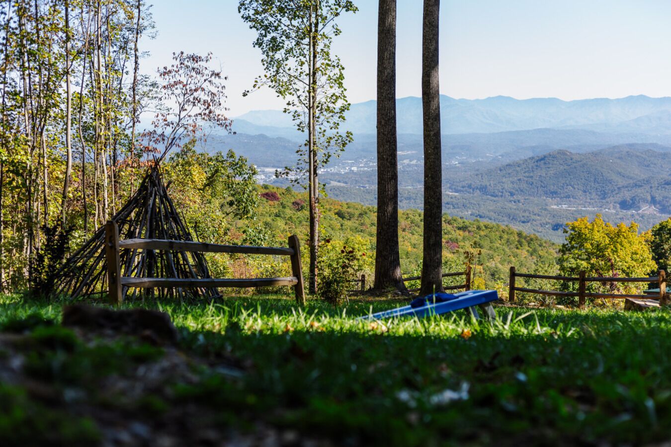 A wooden bench in a grassy area with a view of distant mountains.