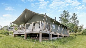 Een tentconstructie met een houten terras en zitgedeelte.