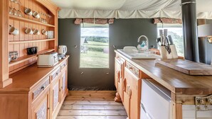 Een keuken met houten kastjes, een spoelbak en uitzicht op het landschap.