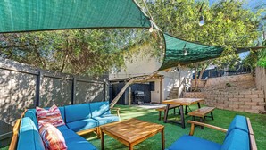 An outdoor patio with blue seating, a wooden table, and a green canopy.