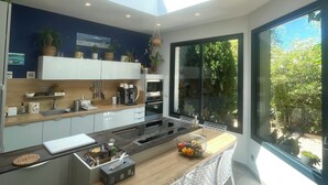 A modern kitchen with a skylight, large windows, and a view of greenery.