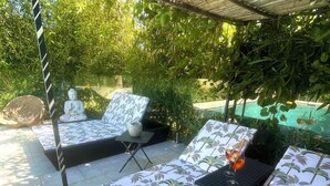 A covered outdoor seating area with patterned cushions and a Buddha statue.