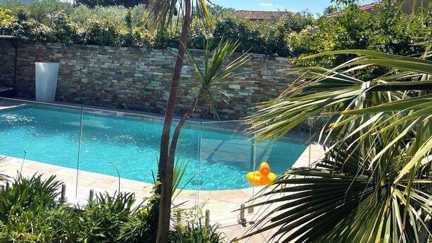 A swimming pool surrounded by lush greenery and a stone wall.