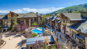 Un resort con varias edificaciones, piscina y montañas al fondo.