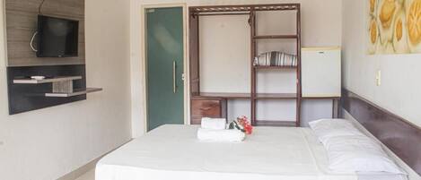 A hotel room with a bed, a TV mounted on the wall, a wardrobe, and a painting on the wall.