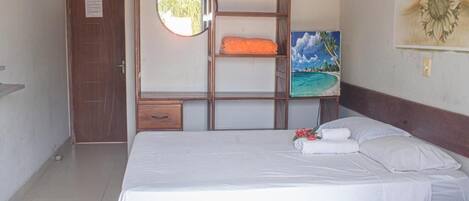 Una habitación con dos camas, un armario de madera, un espejo y un cuadro de una playa.