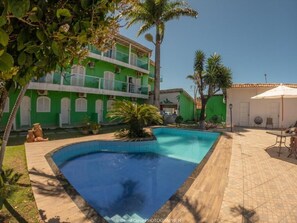 A swimming pool surrounded by a tiled patio, with a building in the background. - Pousada Terra Nostra (Prado)