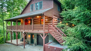 A cabin with a wooden exterior, a balcony, and a staircase leading to the entrance. - Carolina Charm (Banner Elk)