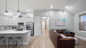 A modern kitchen with white cabinets, stainless steel appliances, and a central island with bar stools.