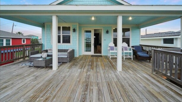 A covered porch with outdoor seating and a door leading to an interior space.