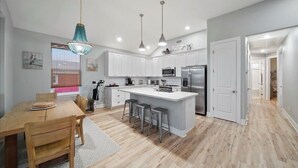 A modern kitchen with white cabinets, stainless steel appliances, and a central island with bar stools.