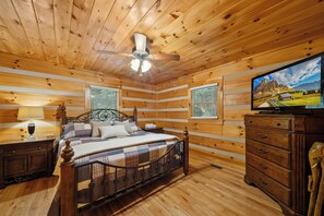 A wooden cabin bedroom with a bed, nightstands, a dresser, and a television. - Uncle Johns Cabin (Vilas)