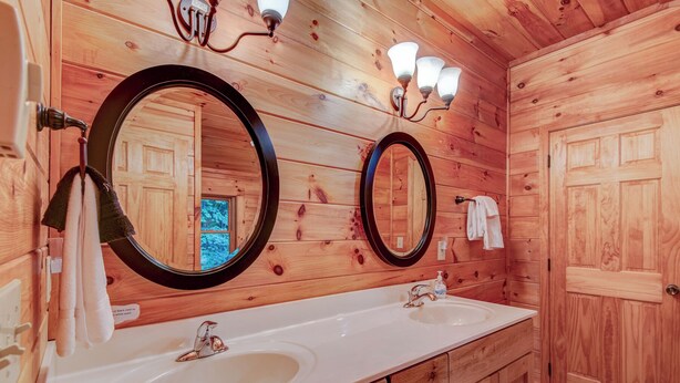 A wooden bathroom with two sinks, a large mirror, and a towel rack. - Uncle Johns Cabin (Vilas)