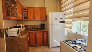 A kitchen with wooden cabinets, a white refrigerator, a microwave, and a gas stove.