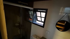 A bathroom with a toilet, sink, and a window. - Fracalanza (Campos do Jordão)