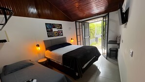 A bedroom with two beds, a wall-mounted TV, and a sliding door leading to a balcony. - Fracalanza (Campos do Jordão)