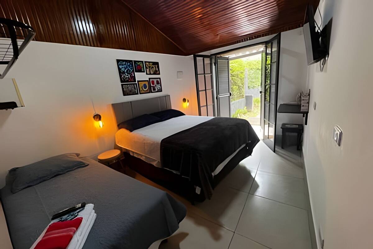 Ein Schlafzimmer mit zwei Betten, einem Wand-Fernseher und einer Schiebetür, die auf einen Balkon führt.