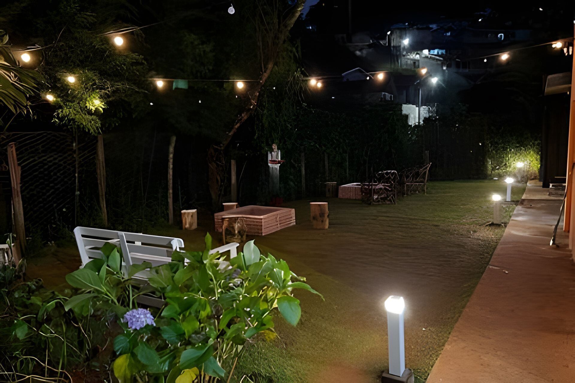An outdoor patio area with string lights, a white bench, and a small table.