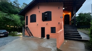 A two-story building with a peach-colored exterior, black-framed windows, and a staircase leading to the entrance. - Fracalanza (Campos do Jordão)