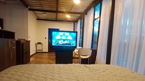 A bedroom with a bed, a television, a chair, and a desk.