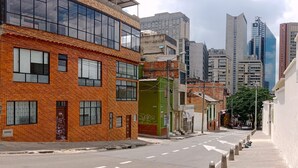 A city street with modern buildings, including a two-story brick building with large windows and a green structure.