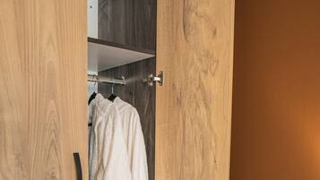A wooden wardrobe with a robe hanging inside.