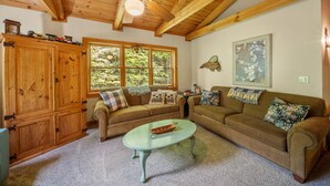 A cozy living room with wooden ceilings, a large window, and a fireplace. - Appalachian Satisfaction (Banner Elk)