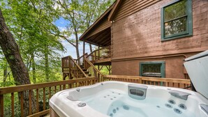 A hot tub on a wooden deck with a view of a rustic building and trees. - Appalachian Satisfaction (Banner Elk)