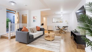 Ein modernes Wohnzimmer mit grauem Sofa, einem runden Couchtisch und einer schwarzen TV-Konsole.
