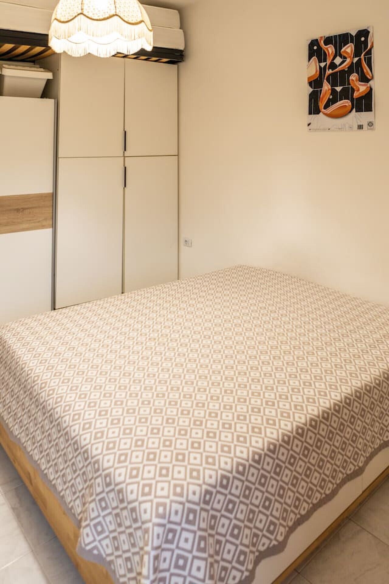 Ein Schlafzimmer mit Bett, Schrank und Wandleuchte.
