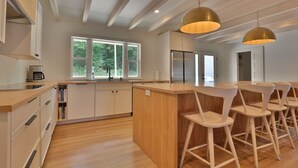 A modern kitchen with a central island, bar stools, and pendant lighting.