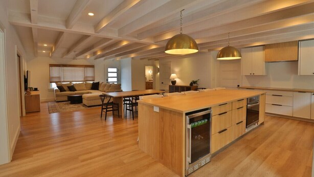 A spacious kitchen with wooden countertops, a central island with a built-in refrigerator, and pendant lighting.
