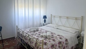 A bedroom with a bed, a chair, a lamp, and a table. - Villa D`Angelo - Camera Matrimoniale (Miracoli)
