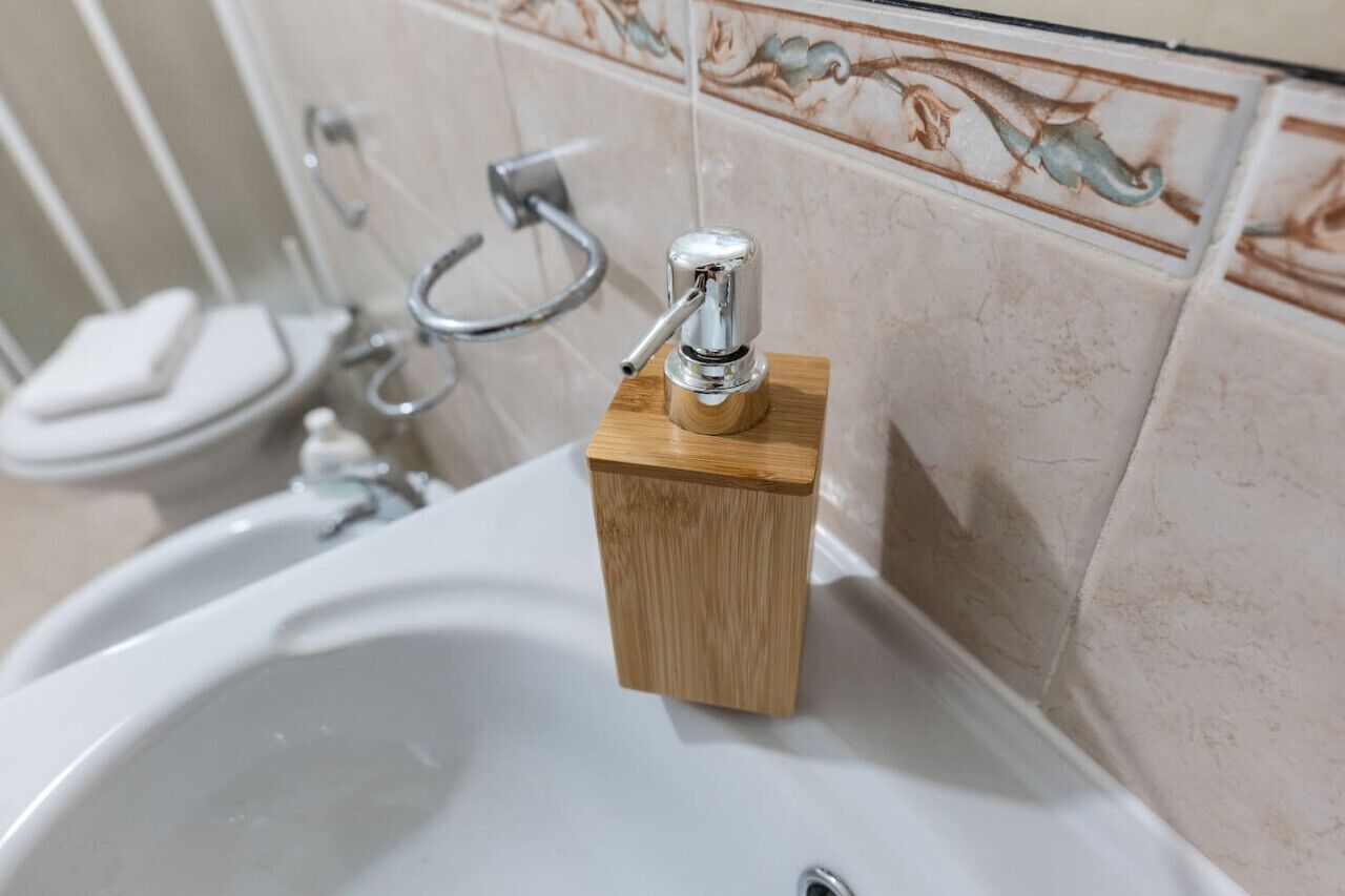 Ein Badezimmer mit einem weißen Waschbecken, einer Holzerzeugnisse-Seifenschale und einer Toilette.