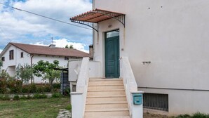 Una casa con puerta verde, escalones color beige y fachada blanca.