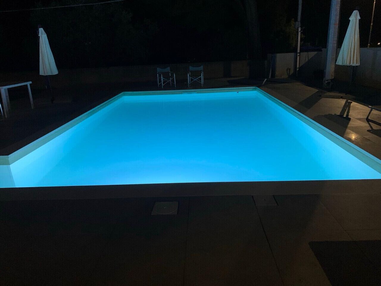 A rectangular swimming pool with a blue light.