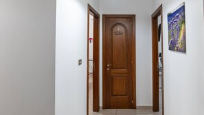 A hallway with a wooden door labeled "Toilet" and a painting of a bicycle on the wall. - Villa D`Angelo - Quadrupla (Miracoli)