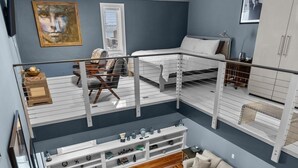 Un espacio habitable de varios niveles con una cama en altillo, un sofá y una escalera.