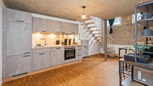 A modern kitchen with grey cabinets, a wooden countertop, and a built-in oven. There is a staircase leading to an upper level. - flair Alte Brauerei I Old town I free parking lot I coffee I WiFi I Xbox IDisney (Kitzingen)